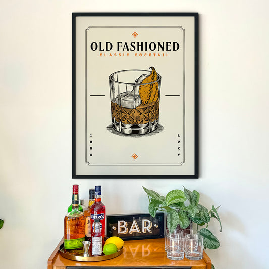 a framed poster of a cocktail glass with a drink inside, placed above a bar counter with various liquor bottles and glasses.