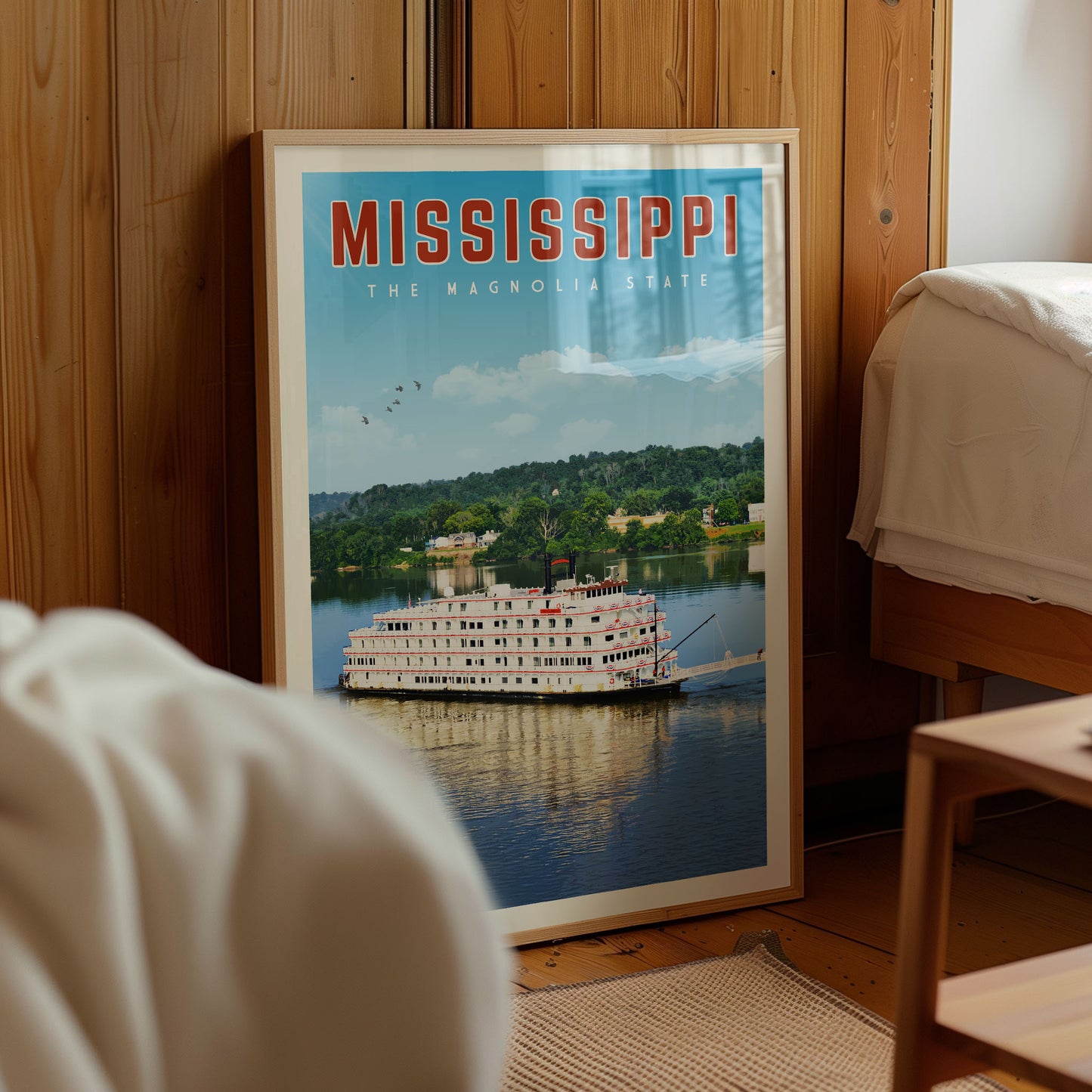 A framed poster of a large white paddle steamboat on a river, with the text "MISSISSIPPI THE MAGNOLIA STATE" prominently displayed.