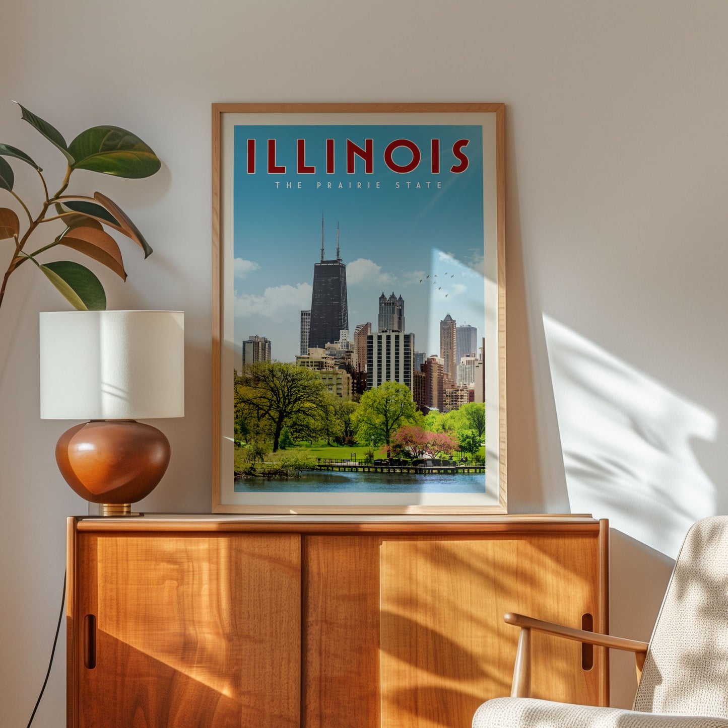 a framed poster of the Chicago skyline, with the text "ILLINOIS THE PRIRAGE STATE" prominently displayed. The poster is hanging on a wooden cabinet, and there is a lamp and a plant in the foreground.