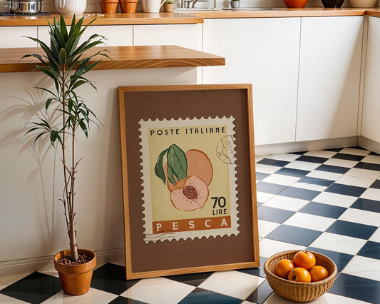 a framed stamp-like artwork depicting a peach, placed on a checkered floor next to a potted plant and a basket of oranges.