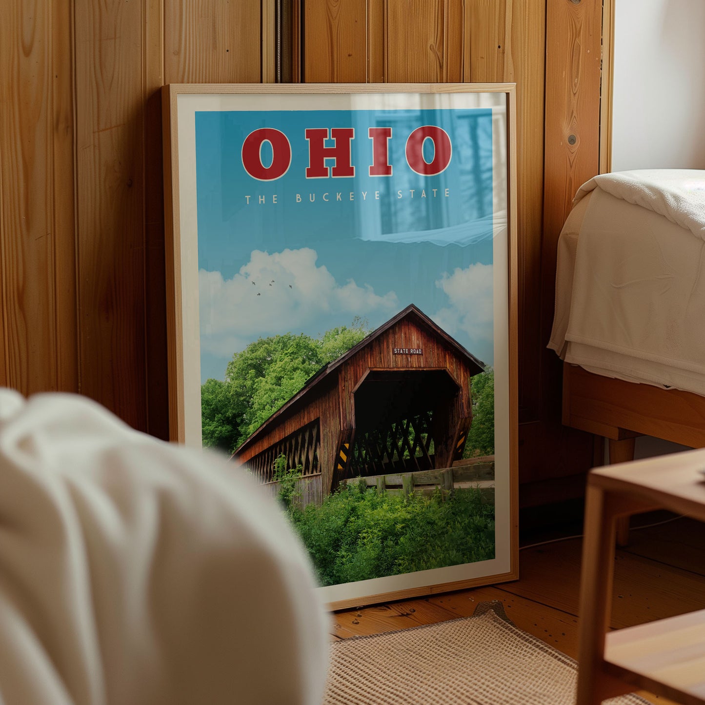 a framed poster of a covered bridge in Ohio, with a clear blue sky and green trees in the background.