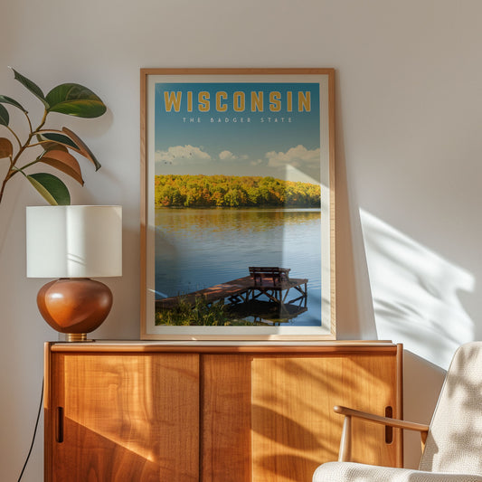 a framed poster of a scenic lake with a dock and a tree, hanging on a wall next to a wooden cabinet and a lamp.