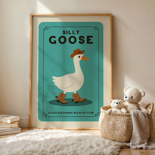 a framed poster of a cartoon duck wearing a cowboy hat, with the text "Silly GOOSE" and "LITTLE EXPLORERS WILDLIFE CLUB" below it. Next to the poster, there is a woven basket containing two teddy bears.