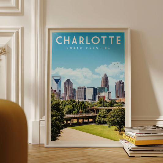 A framed poster of the Charlotte, North Carolina skyline, featuring the city's iconic skyscrapers and greenery, is displayed on a wall.