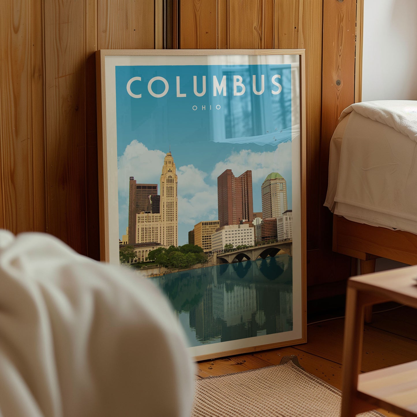A framed poster of the city of Columbus, Ohio, featuring a skyline with tall buildings and a river in the foreground.