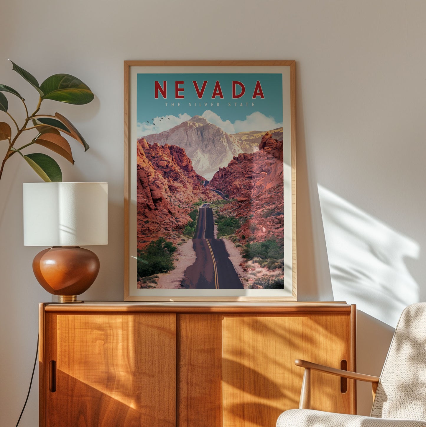 a framed poster of a scenic road winding through a mountainous landscape, with the text "NEVADA THE SILVER STATE" prominently displayed.