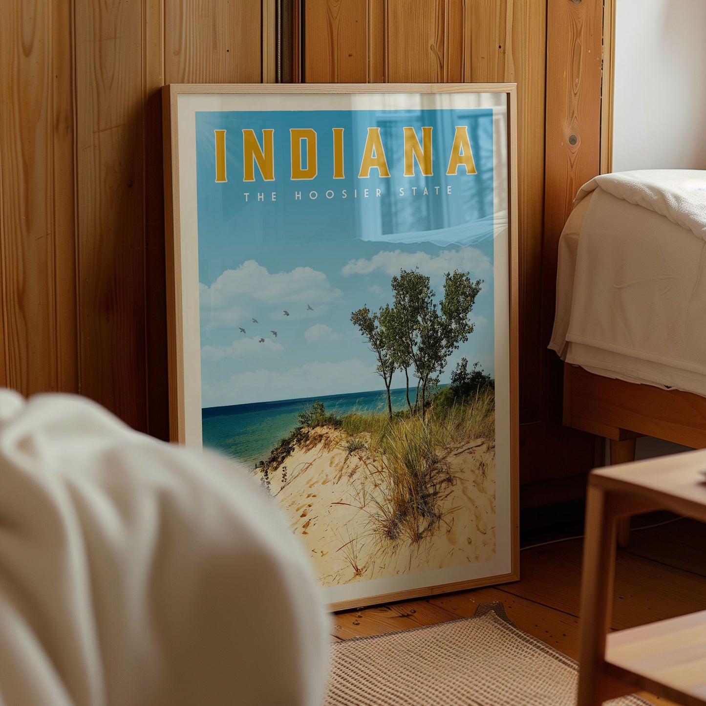 A framed poster of a beach scene with trees and a blue sky, displaying the text "INDIANA THE HOOSIER STATE" in the top half.