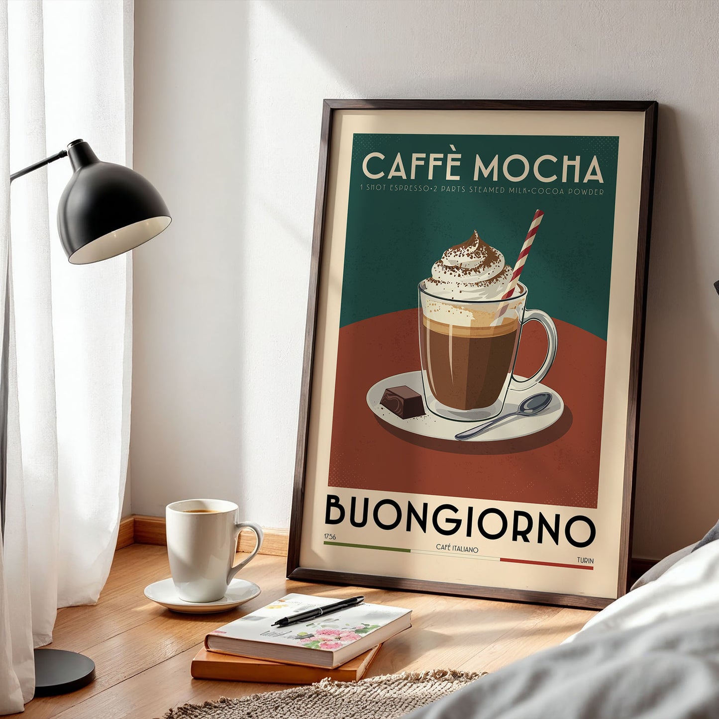 a framed poster of a coffee mug with a whipped cream topping, placed on a wooden table next to a lamp and a book.