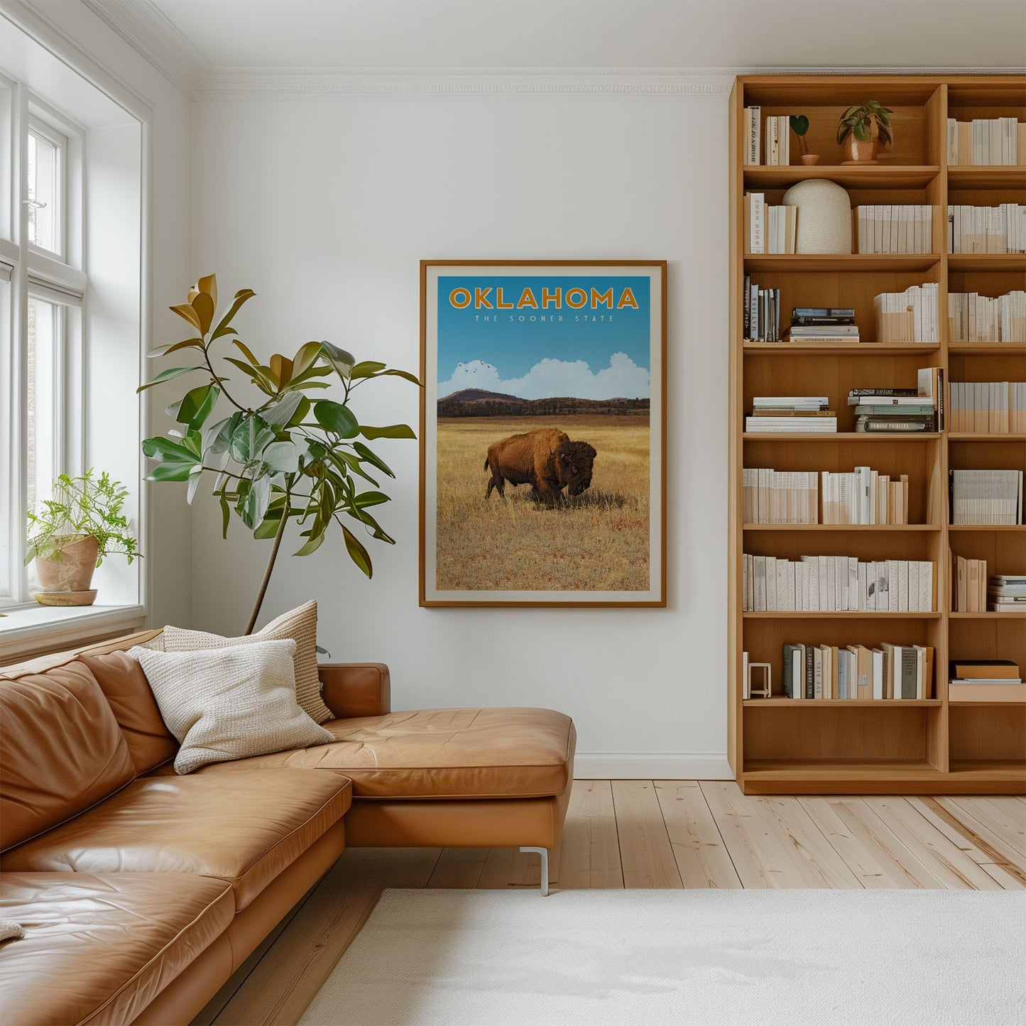a living room with a large bookshelf filled with books, a comfortable leather couch, and a framed poster of a buffalo in the grass.