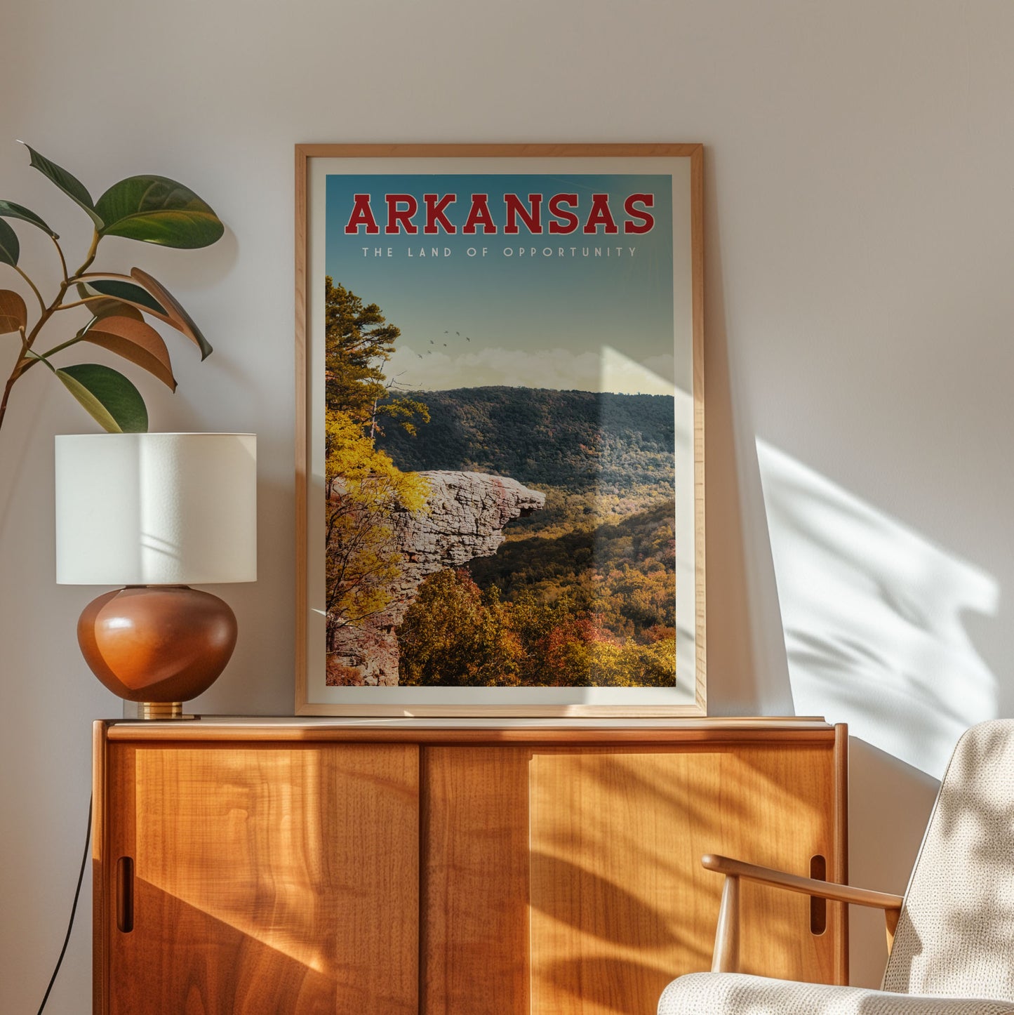 a framed poster of a scenic mountain landscape with the text "ARKANSAS - The land of opportunity" on it, placed on a wooden cabinet or shelf.