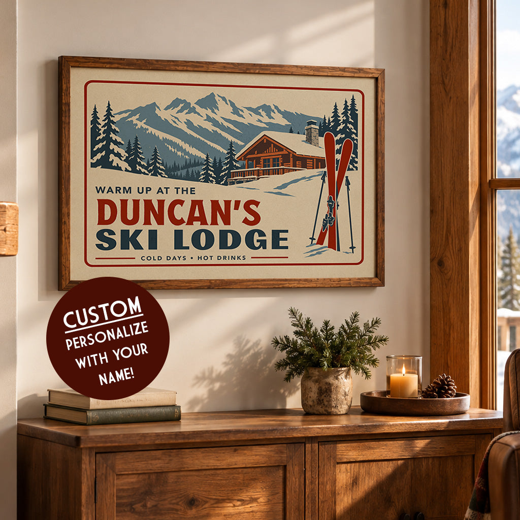 a framed poster of a ski lodge with a mountain backdrop, along with a potted plant and some candles on a wooden table.