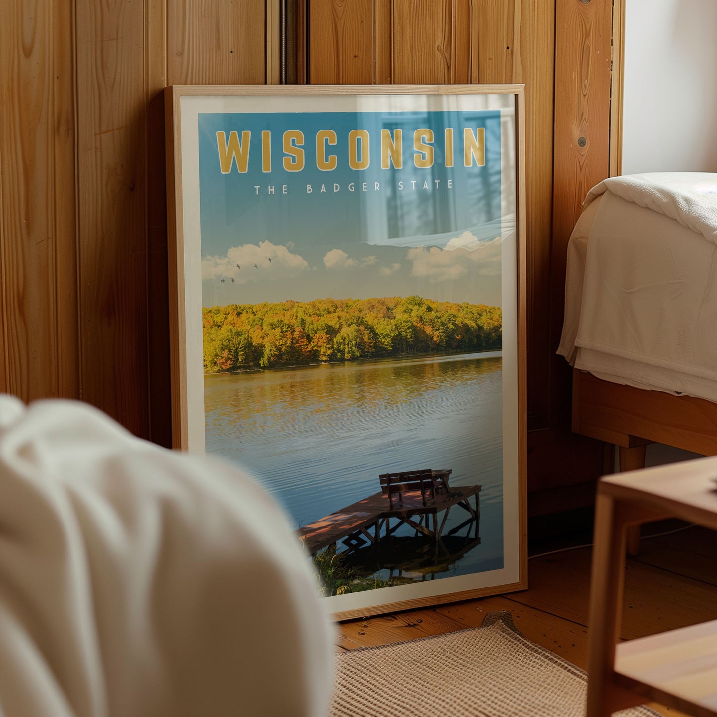 A framed poster of a scenic lake surrounded by trees and a dock, with the text "WISCONSIN THE BADGER STATE" prominently displayed.