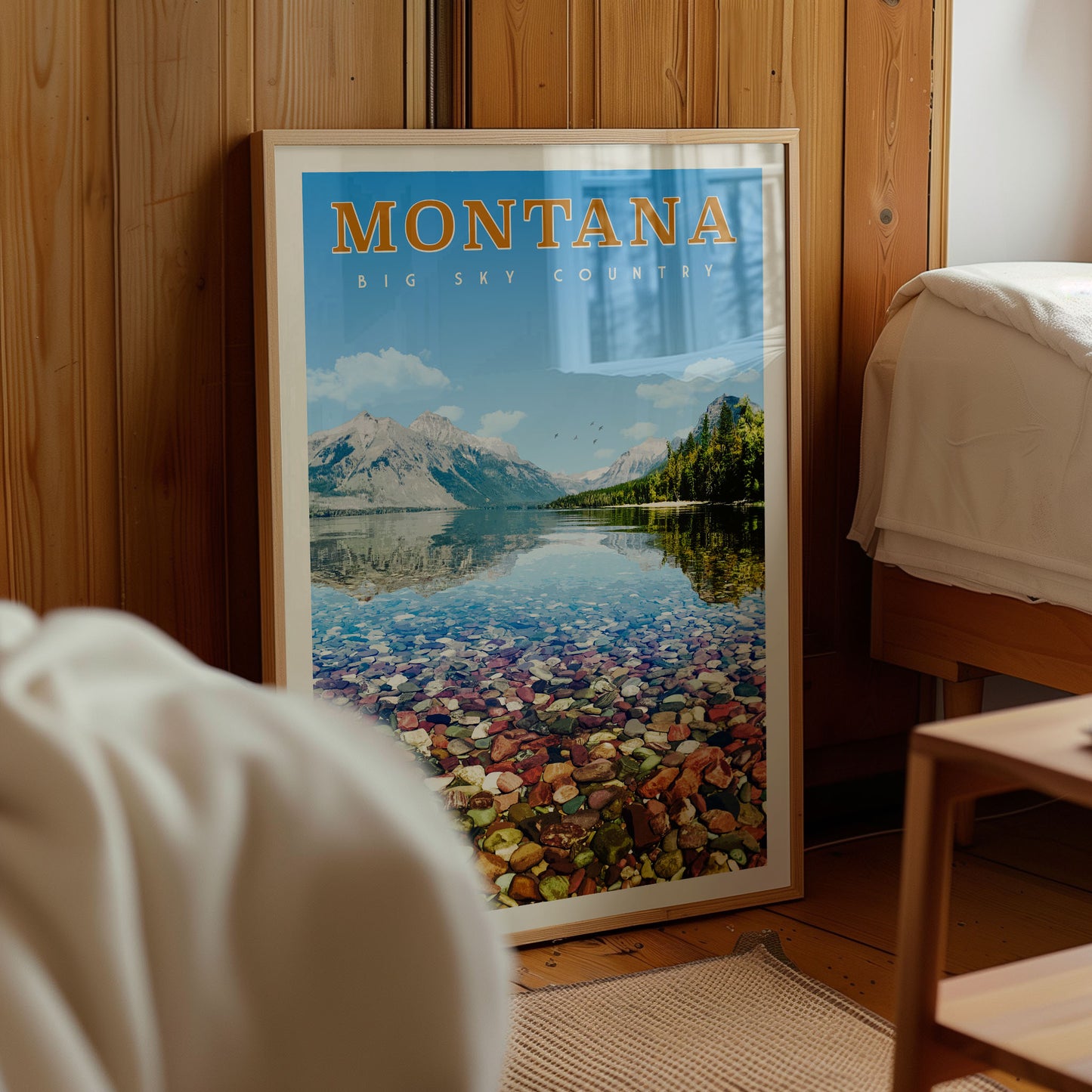 A framed poster of a scenic mountain landscape with a lake and mountains in the background, displayed in a room with wooden walls.