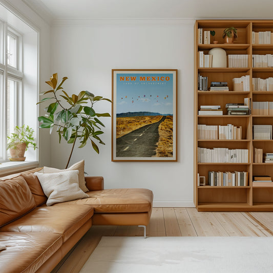 a cozy living room with a large bookshelf filled with books, a comfortable leather couch, and a framed poster of a desert road in New Mexico.