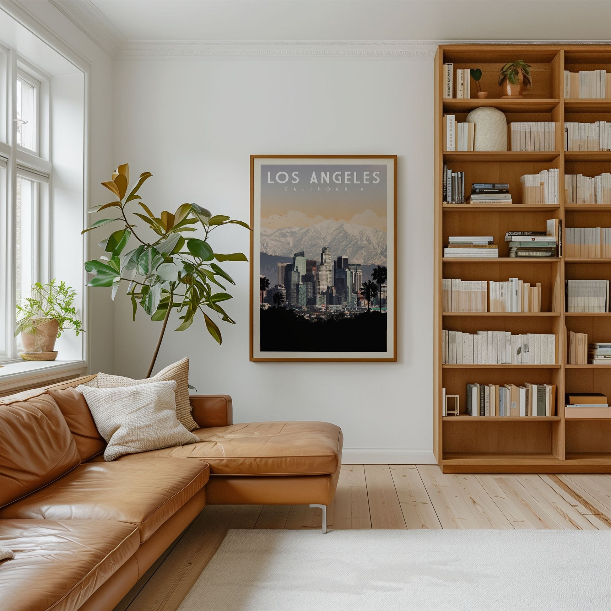 a cozy living room with a large window, a comfortable leather couch, a bookshelf filled with books, and a framed poster of Los Angeles, California.