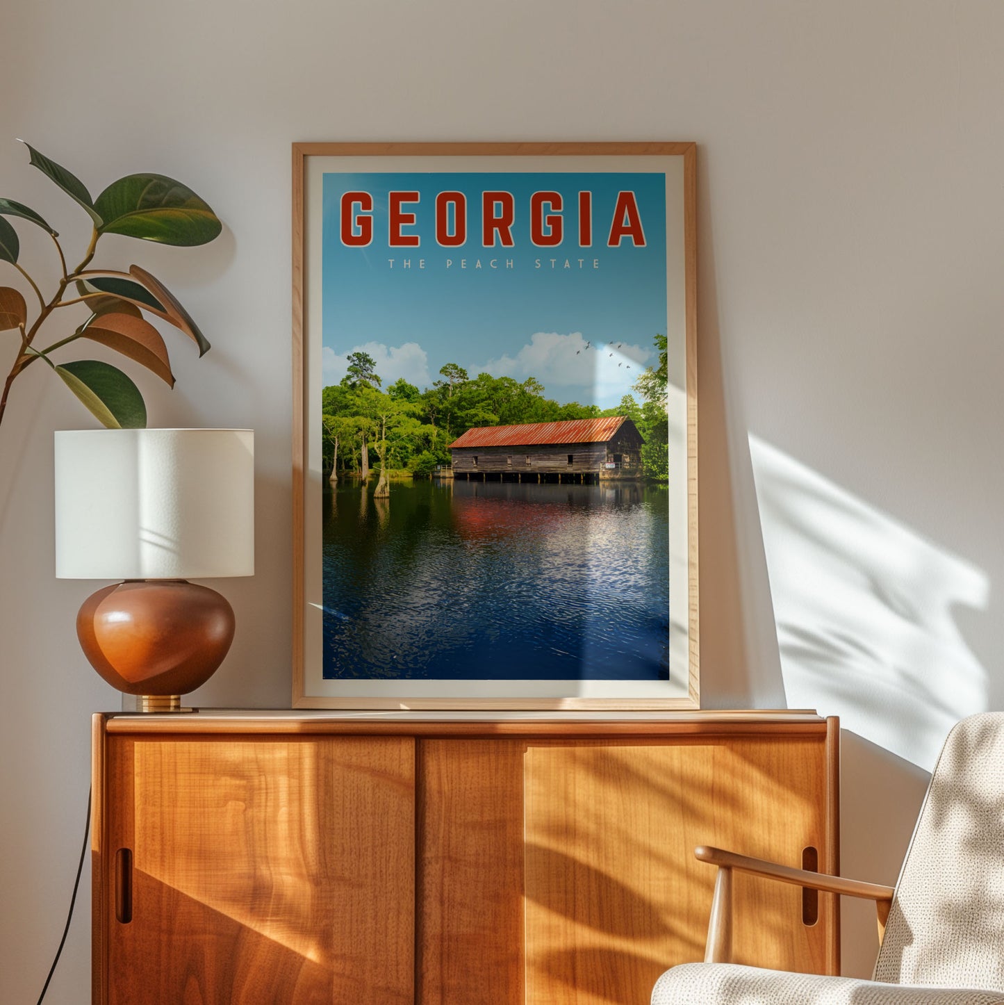 a framed poster of a scenic view of a lake with a wooden cabin, hanging on a wall next to a lamp and a wooden cabinet.
