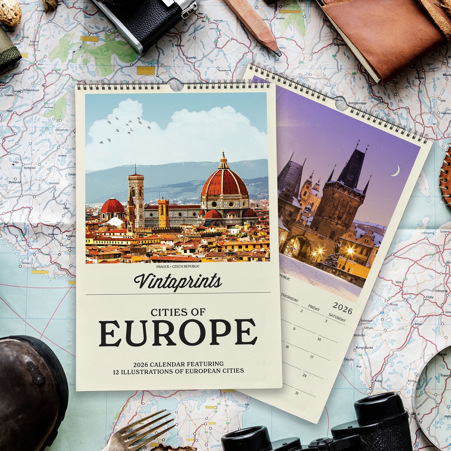 a calendar with a photo of a city and a map, along with various travel-related items such as a camera, a magnifying glass, and a compass.