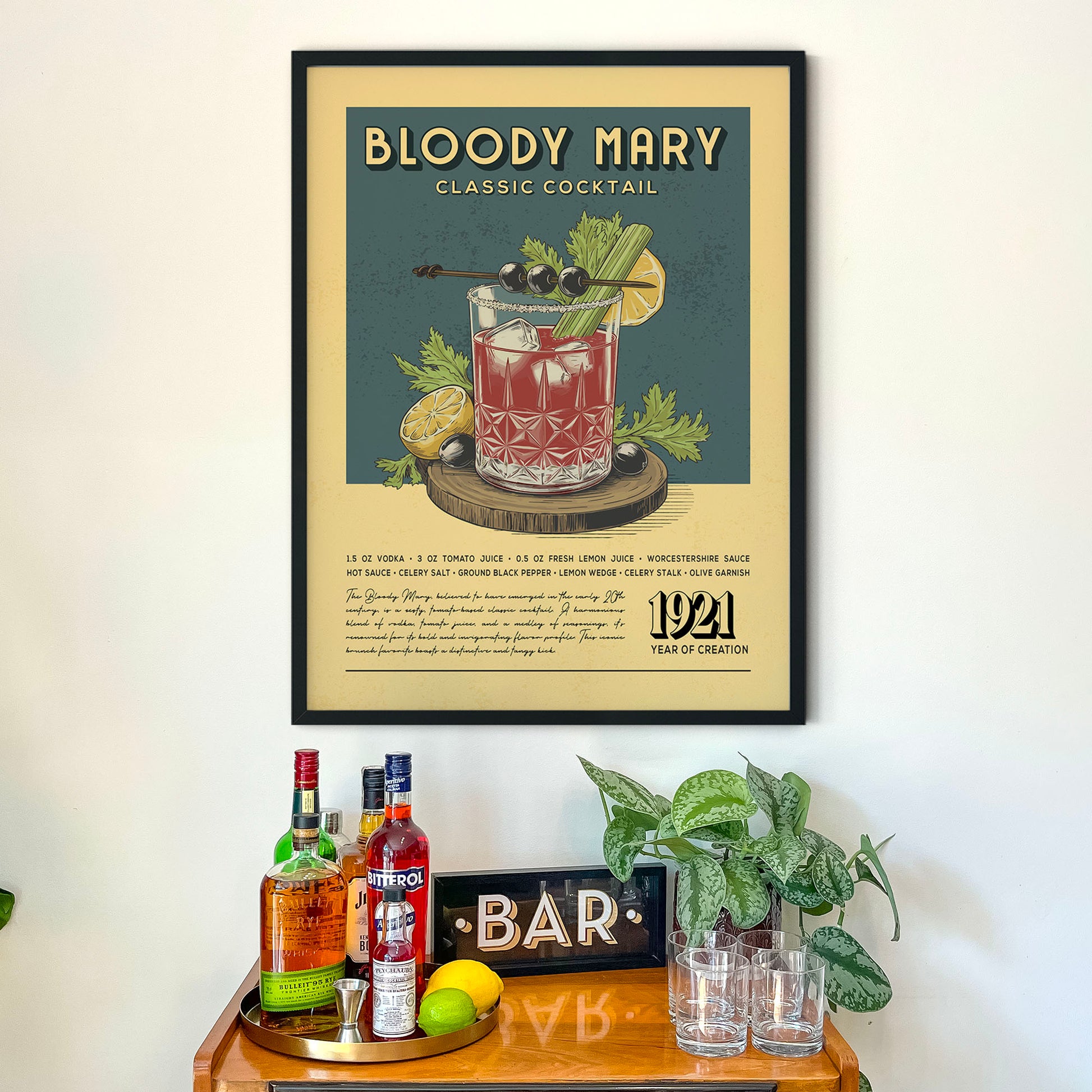 a framed poster of a Bloody Mary cocktail hanging on a wall above a wooden bar counter with various liquor bottles and glasses.