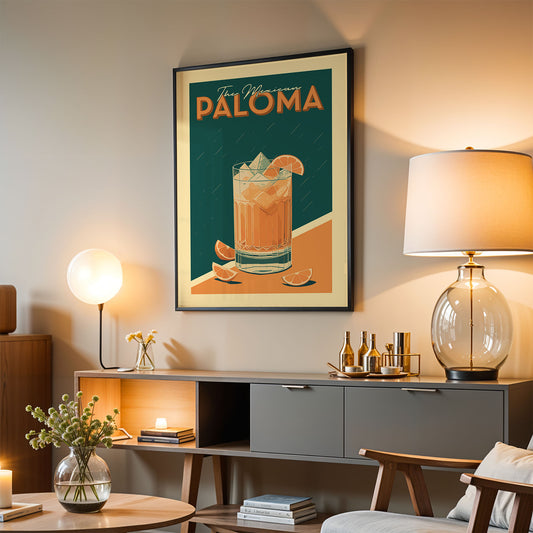 a framed poster of a cocktail glass with a drink, hanging on a wall above a wooden cabinet with a glass lamp and other decorative items.