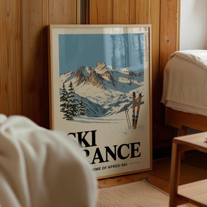 A framed poster of a snowy mountain landscape with ski equipment, displayed in a room with wooden walls.