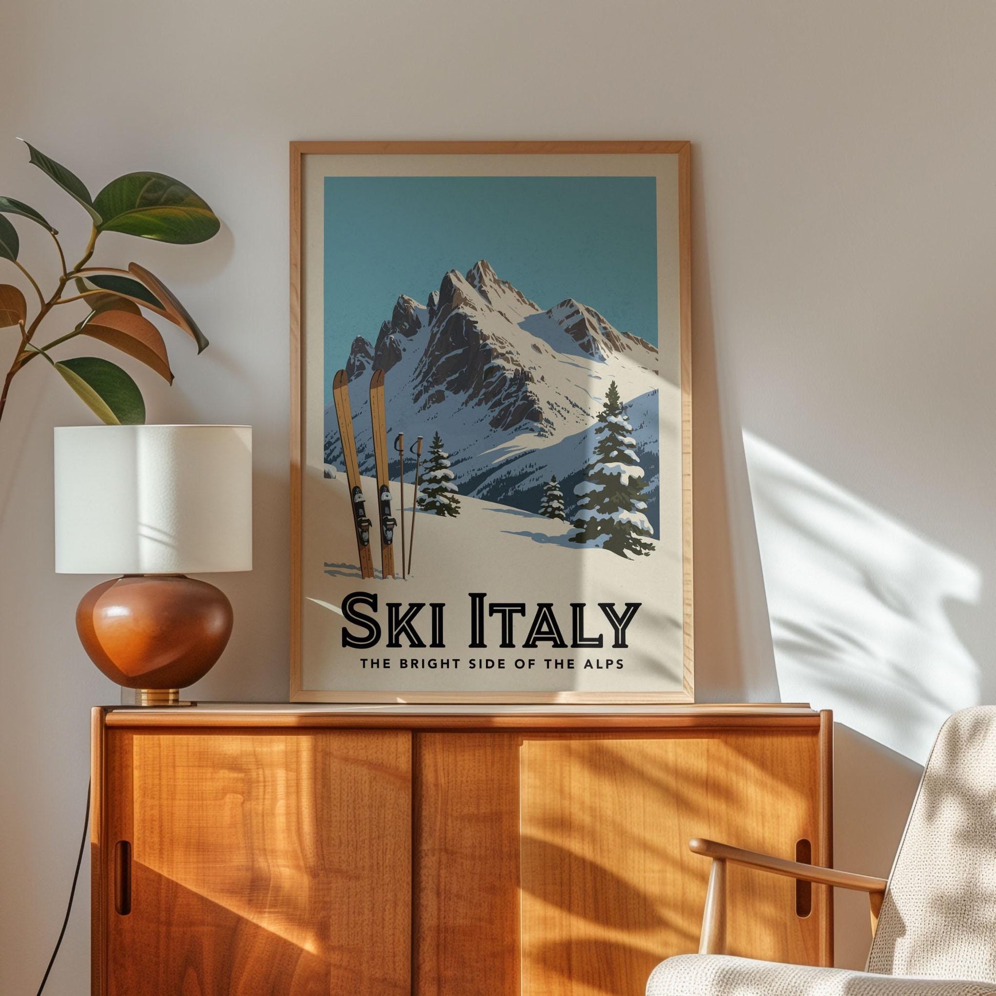 A framed poster of a snowy mountain landscape with skis, hanging on a wall above a wooden cabinet.