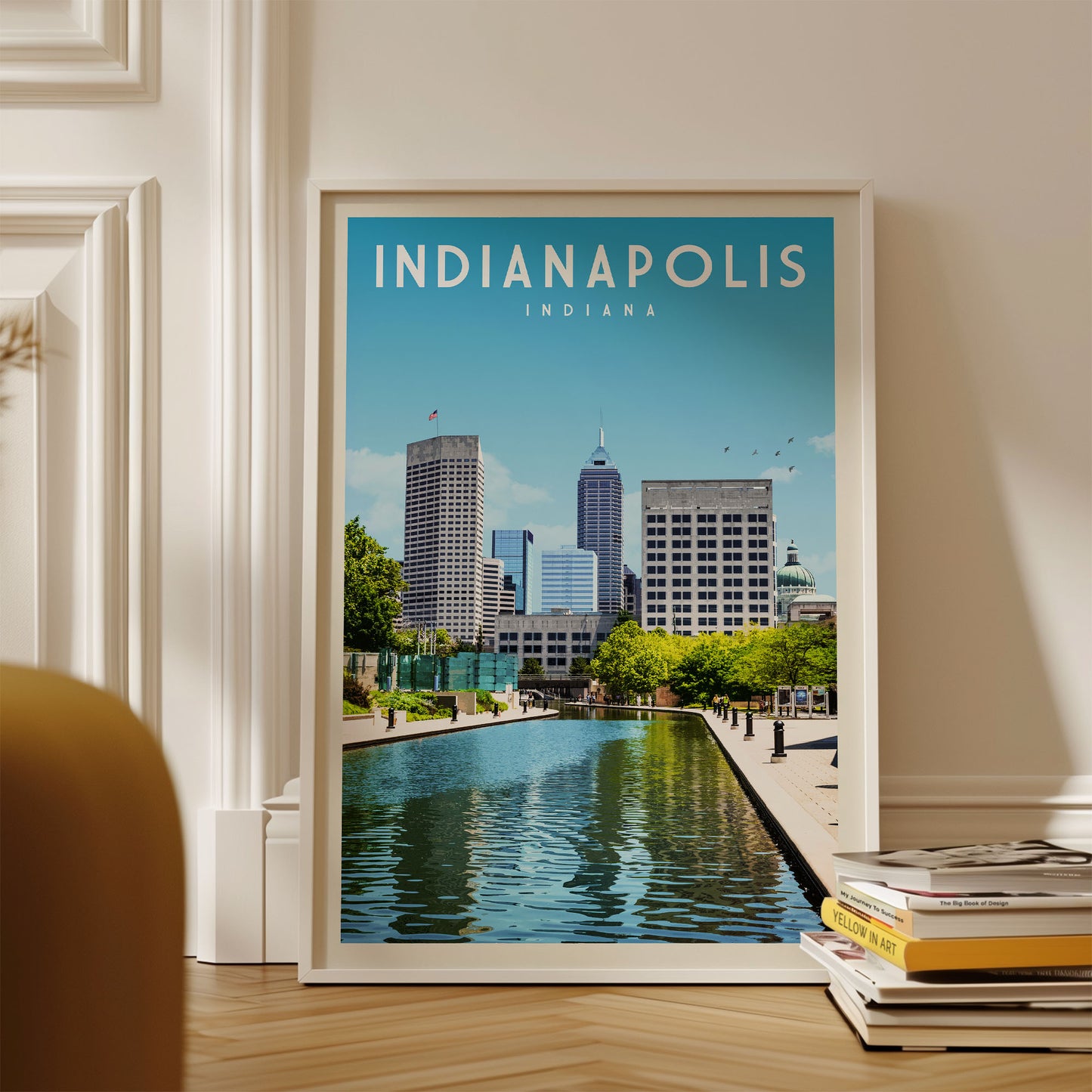 A framed poster of the Indianapolis skyline, featuring the city's iconic buildings and a reflecting pool, is displayed on a wall.