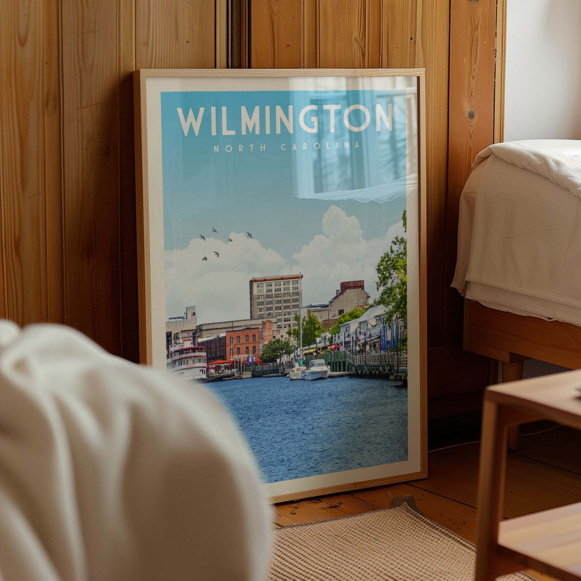 A framed poster of a cityscape with a river in the foreground, displaying the text "WILMINTON NORTH CAROLINA" and a scenic view of the city.