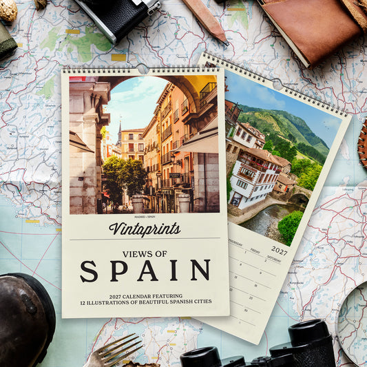 a calendar with a photo of a city in Spain, surrounded by various travel-related items such as a map, a camera, and a pair of binoculars.