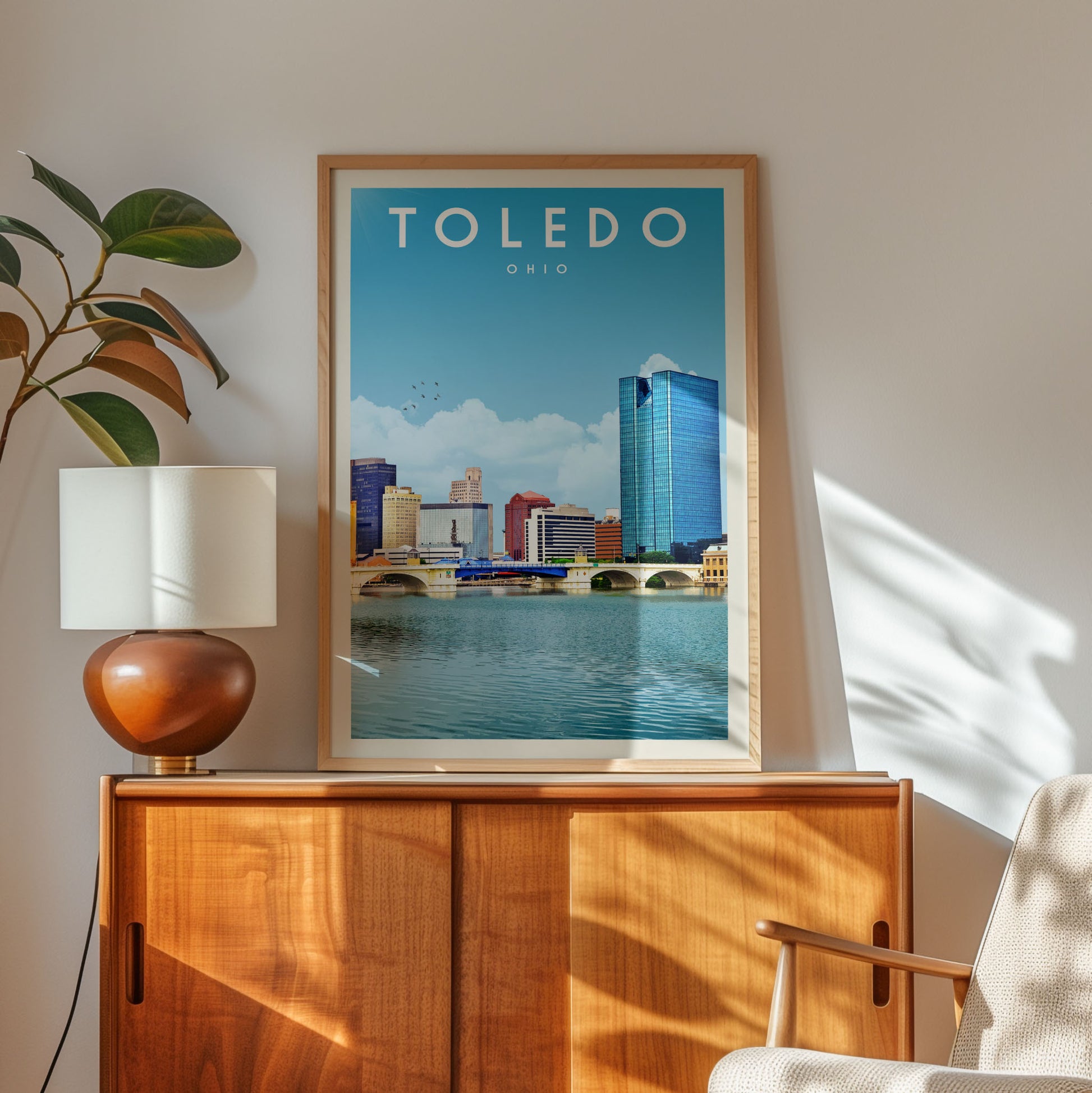 a framed poster of the city of Toledo, Ohio, with a view of the city's skyline and a body of water in the foreground.