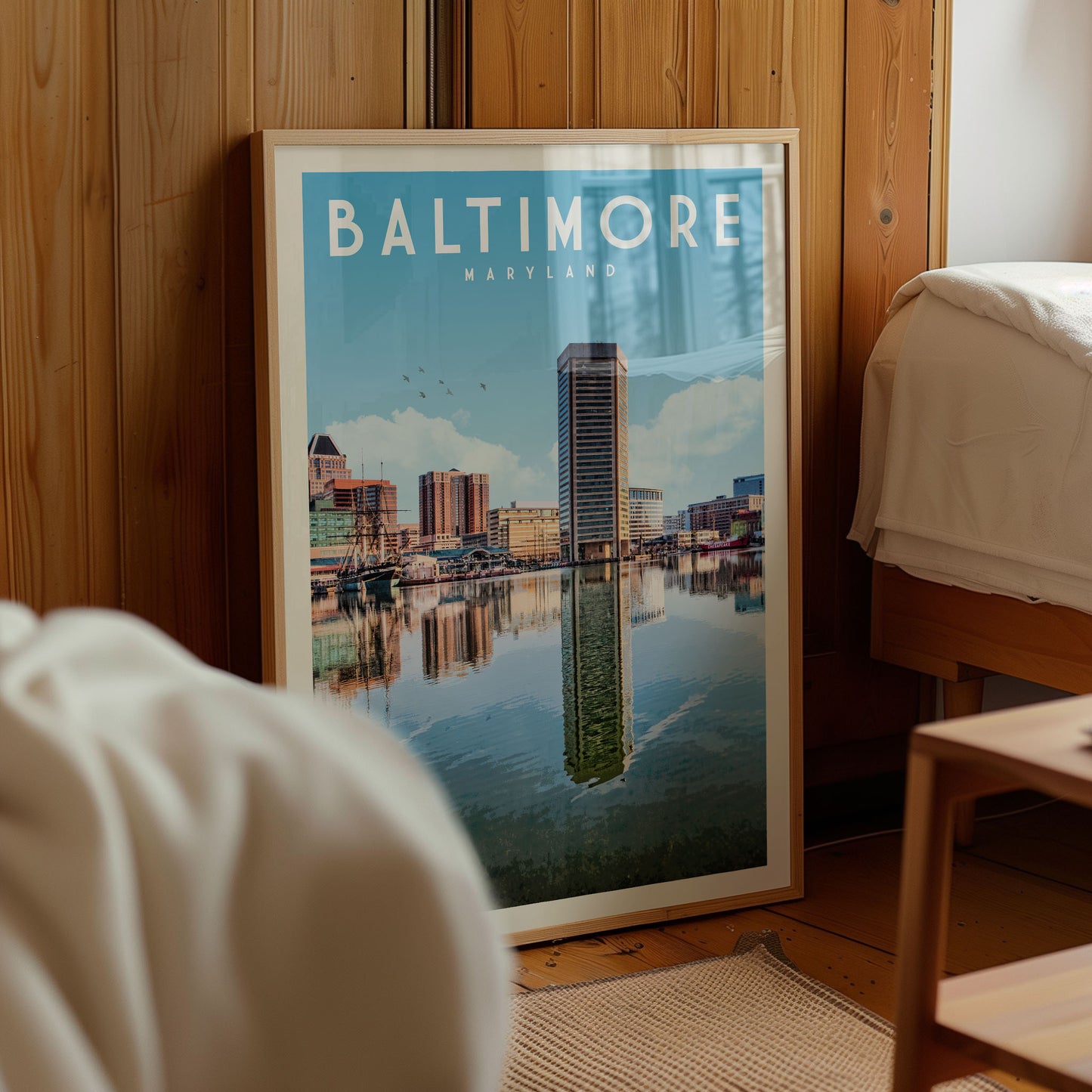 A framed poster of the Baltimore skyline, featuring the city's iconic buildings and water, is displayed in a room with wooden walls.