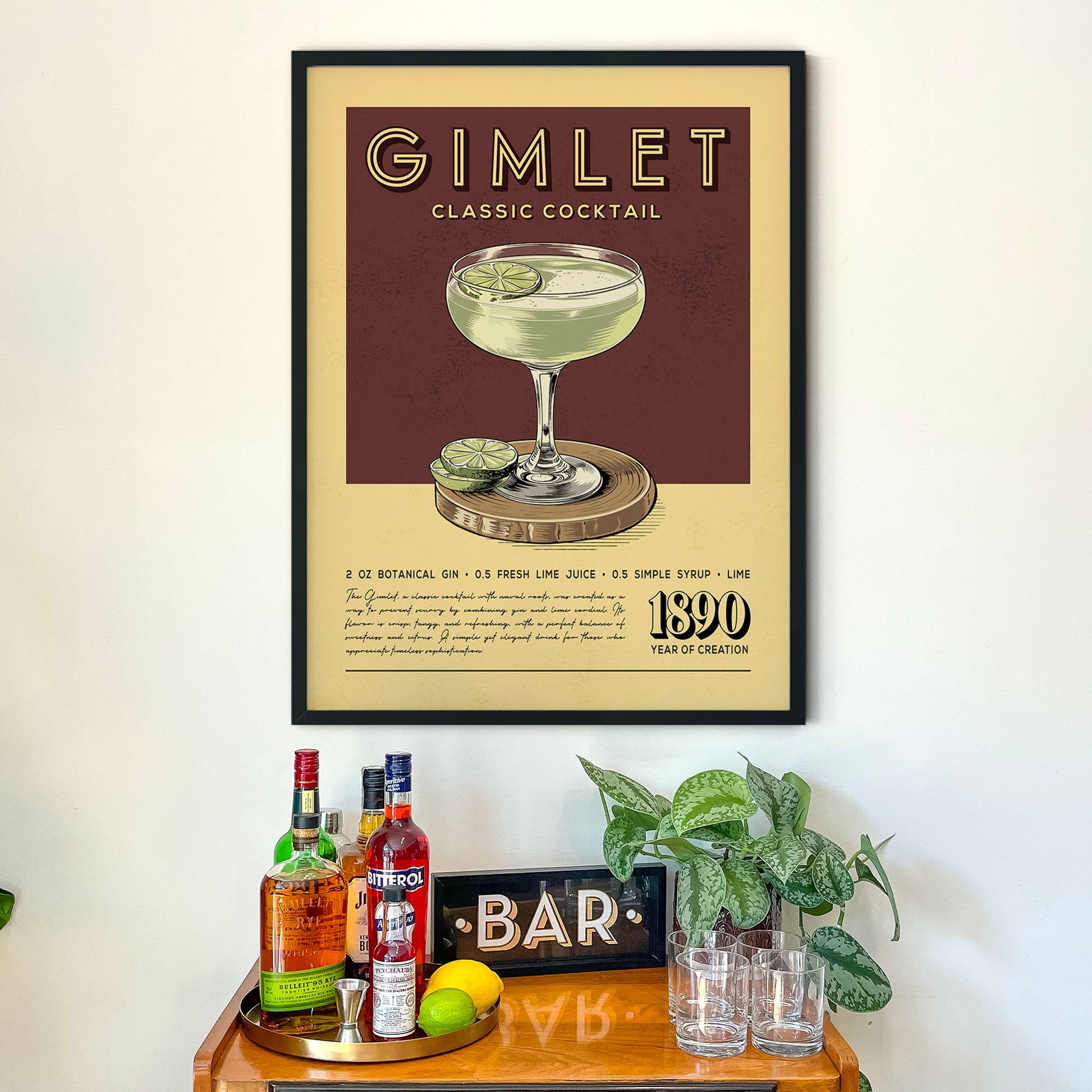 a framed poster of a cocktail recipe, a wooden bar display with various liquor bottles, and a potted plant.