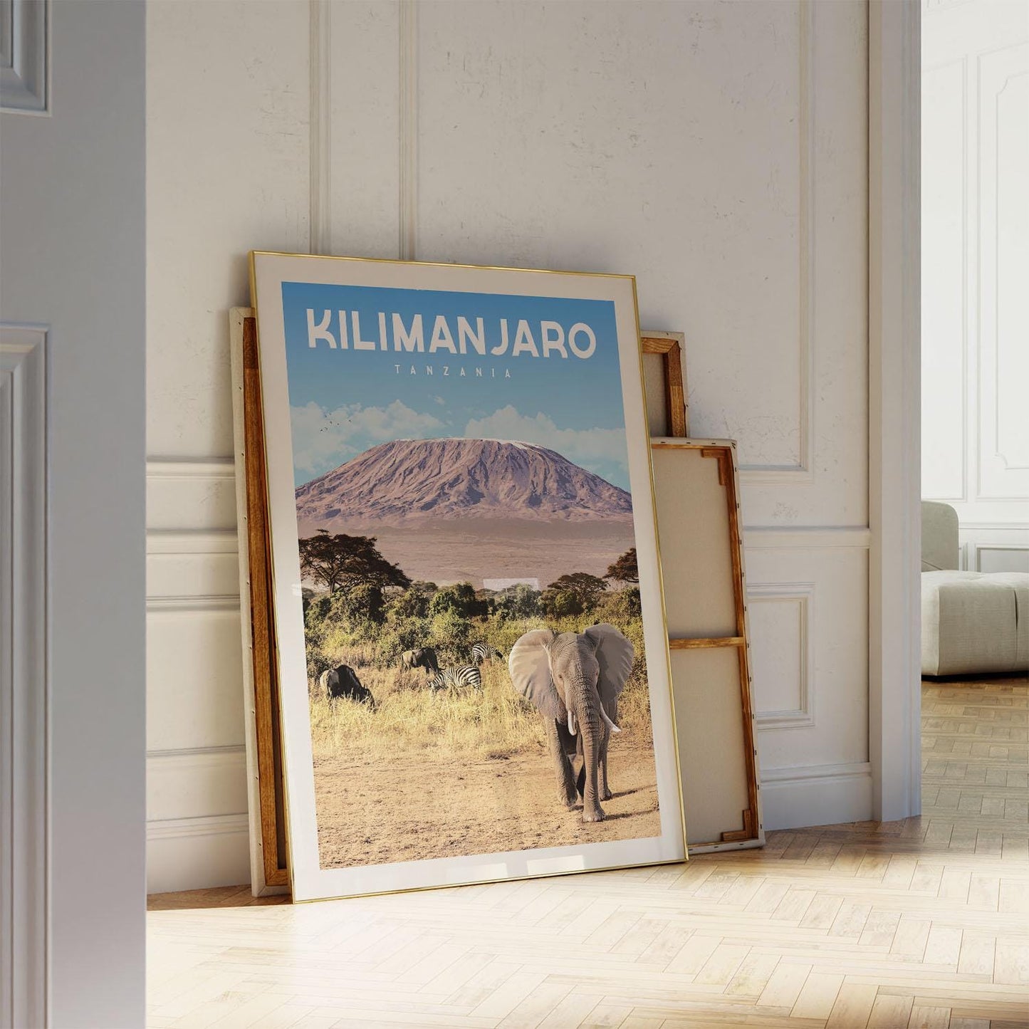 A large framed poster of a mountain landscape with an elephant in the foreground, displayed on a wall in a room.