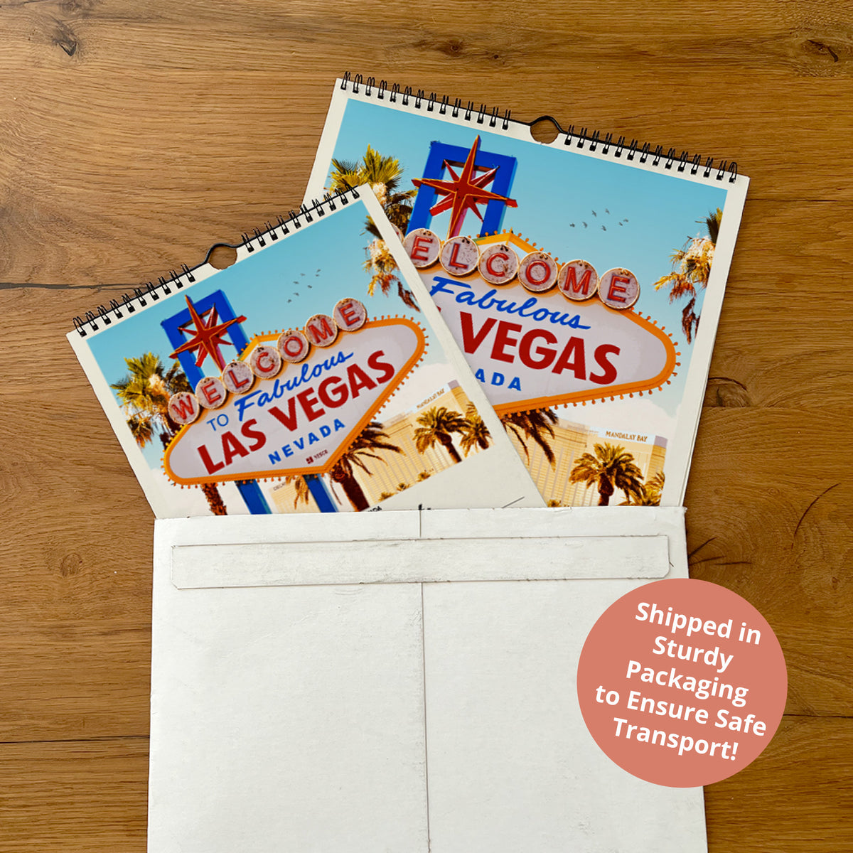 A calendar featuring the iconic Las Vegas sign is placed inside a white envelope, with a shipping label indicating it was sent in a sturdy package to ensure safe transport.