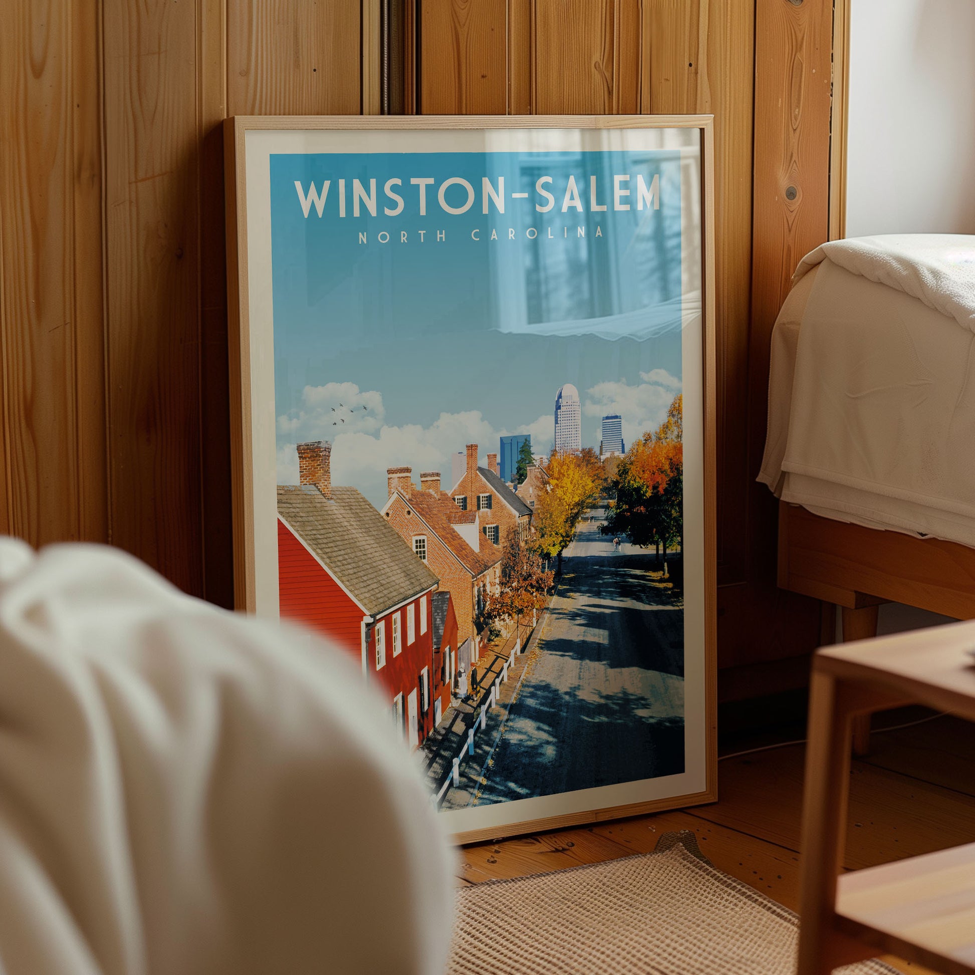 A framed poster of Winston-Salem, North Carolina, featuring a street scene with colorful buildings and trees.