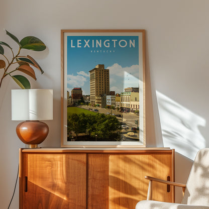 A framed poster of Lexington, Kentucky, featuring a cityscape with buildings and trees, is displayed on a wooden cabinet in a room with a lamp and a plant.