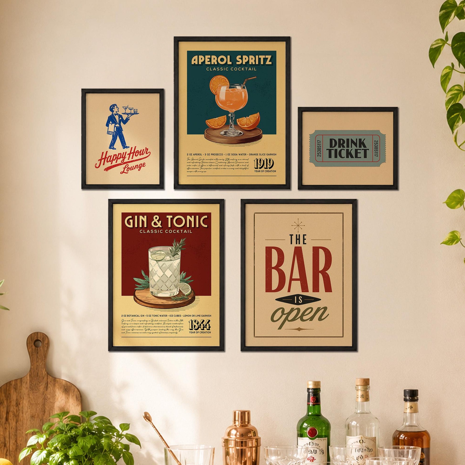 a wall with five framed vintage-style advertisements for bars and cocktails, including a poster for Aperol Spritz, a Gin & Tonic poster, and a framed ticket sign for The Bar is open. There are also several bottles of alcohol displayed on a shelf below the framed advertisements.