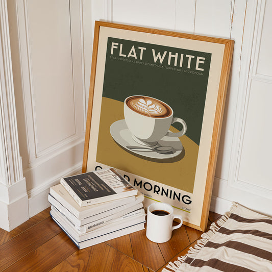 a framed poster of a cup of coffee with the text "FLAT WHITE" and "GOOD MORNING" on it, along with a stack of books and a mug of coffee on the floor.
