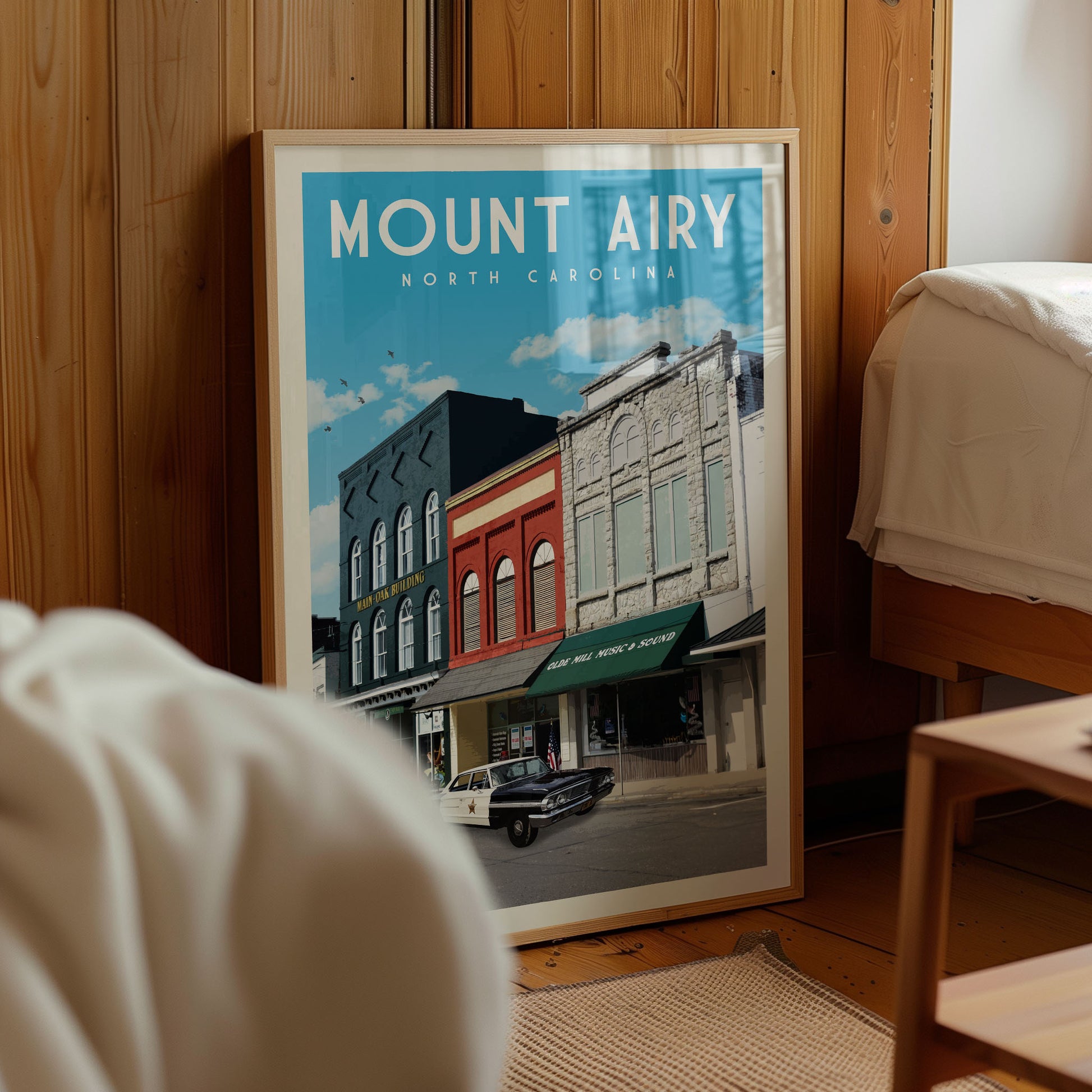 a framed poster of a street scene in North Carolina, with a car parked on the street and buildings in the background.