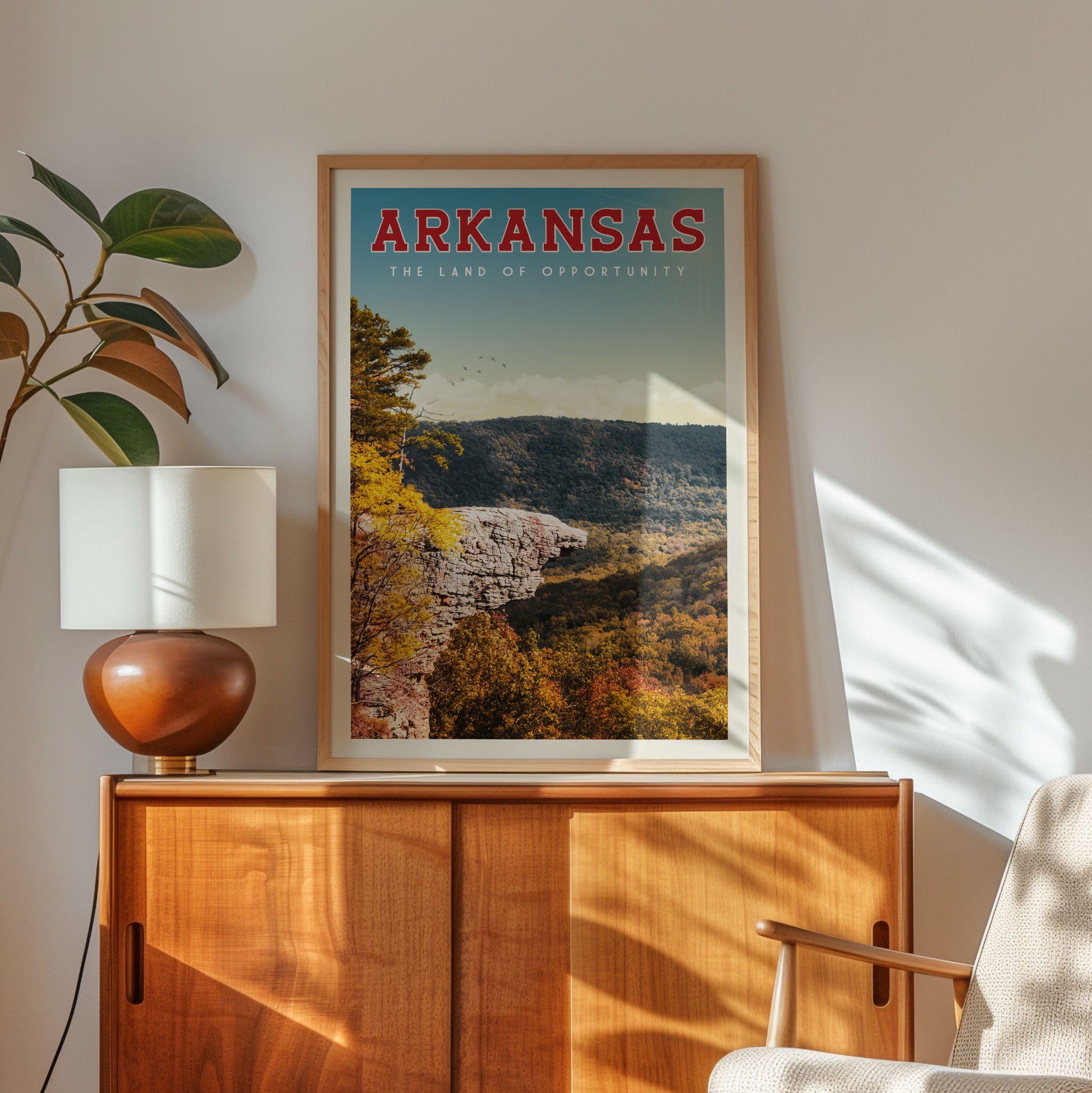 a framed poster of a scenic mountain landscape with the text "ARKANSAS - The land of opportunity" on it, placed on a wooden cabinet or shelf.