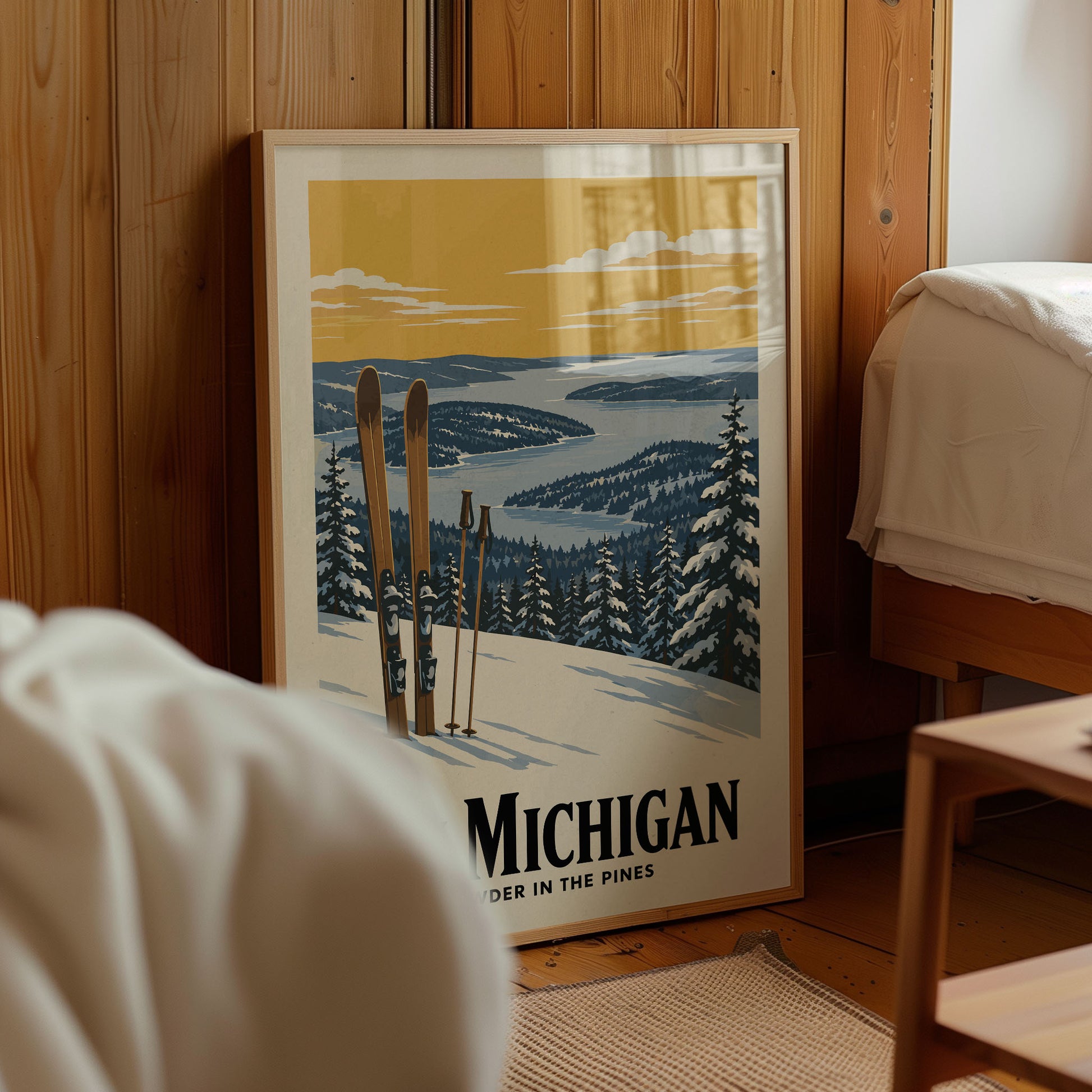A framed poster of a snowy mountain landscape with skis and a cabin in the background, displayed in a room with a wooden wall.