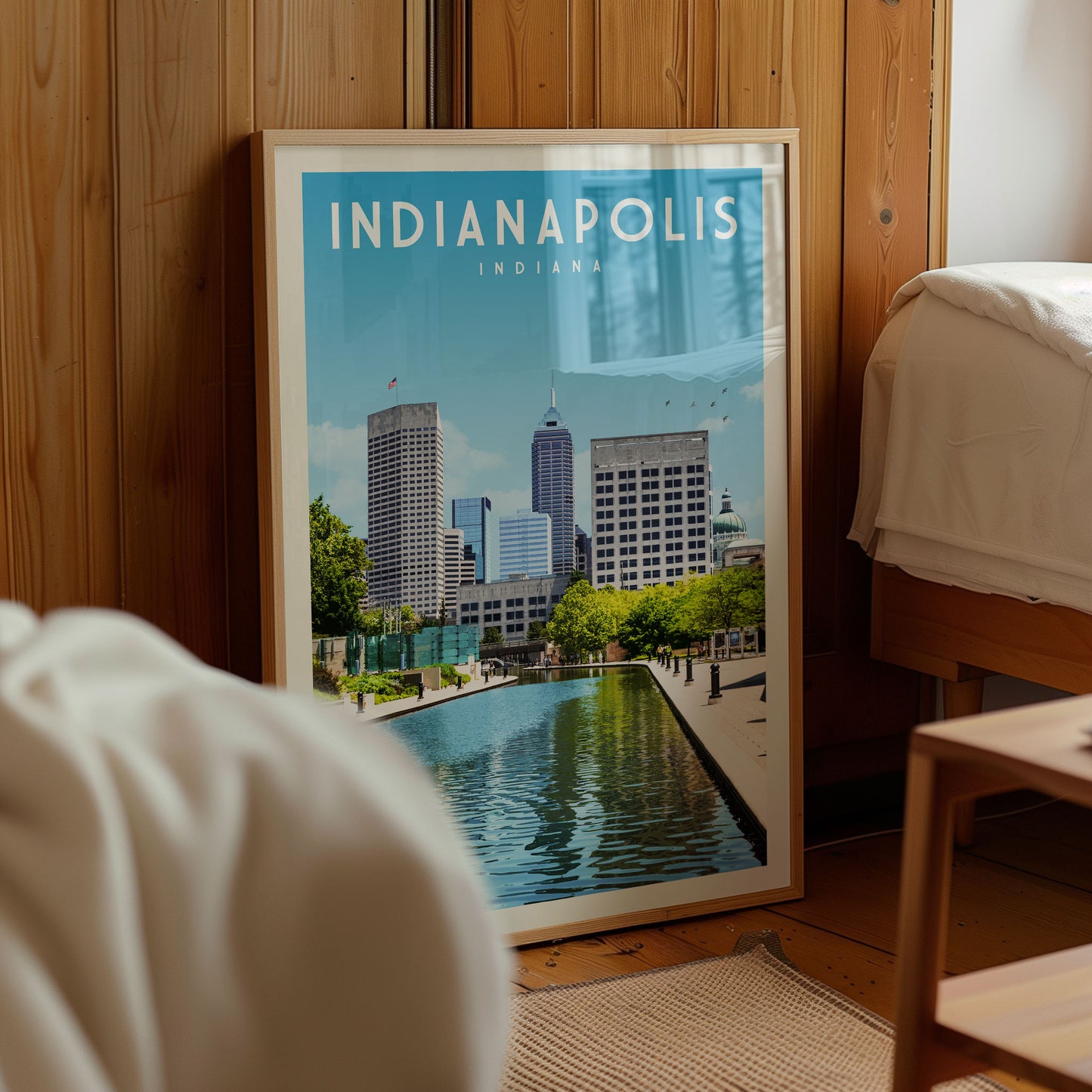 A framed poster of the skyline of Indianapolis, Indiana, with a large body of water in the foreground.