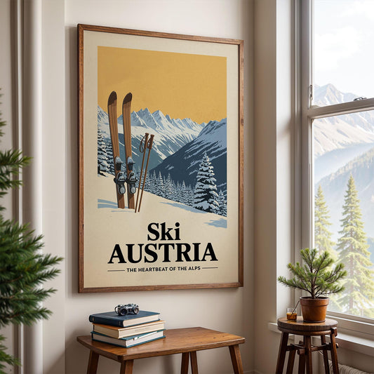 A framed poster of a snowy mountain landscape with skis and trees, hanging on a wall in a room with a window and a small table with books and a plant.