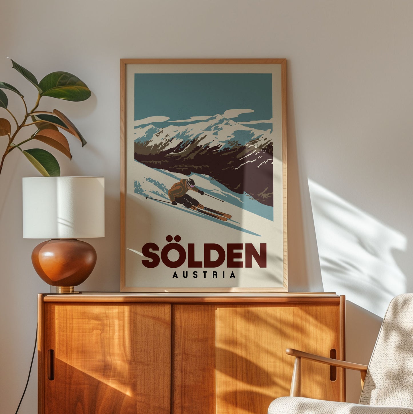 a framed poster of a skier on a mountain, with the text "Sölden Austria" below it. The poster is displayed on a wooden cabinet, and there is a lamp and a plant in the foreground.