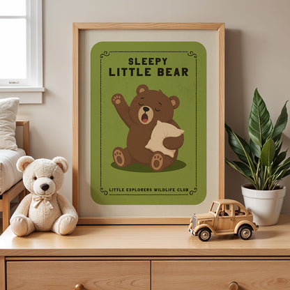 a framed poster of a sleeping bear with the text "SLEEPY LITTLE BEAR" and the logo of the "Little Explorers Wildlife Club". Next to the poster, there is a stuffed teddy bear and a toy truck on a wooden dresser.