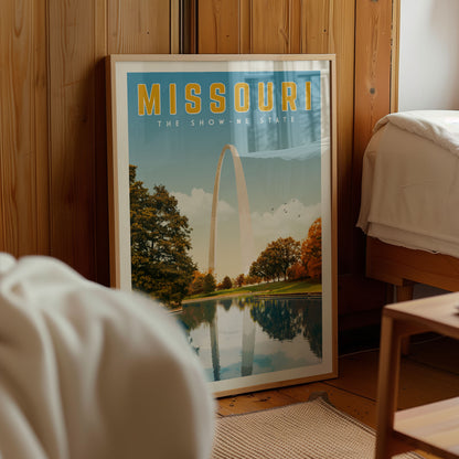 A framed poster of the Gateway Arch in Missouri, with a scenic landscape featuring the arch and trees reflected in a body of water.