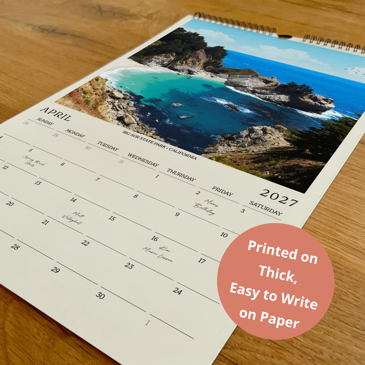 A wall calendar with a scenic coastal landscape photo on the cover, displaying the days of the week and dates for the month of April.