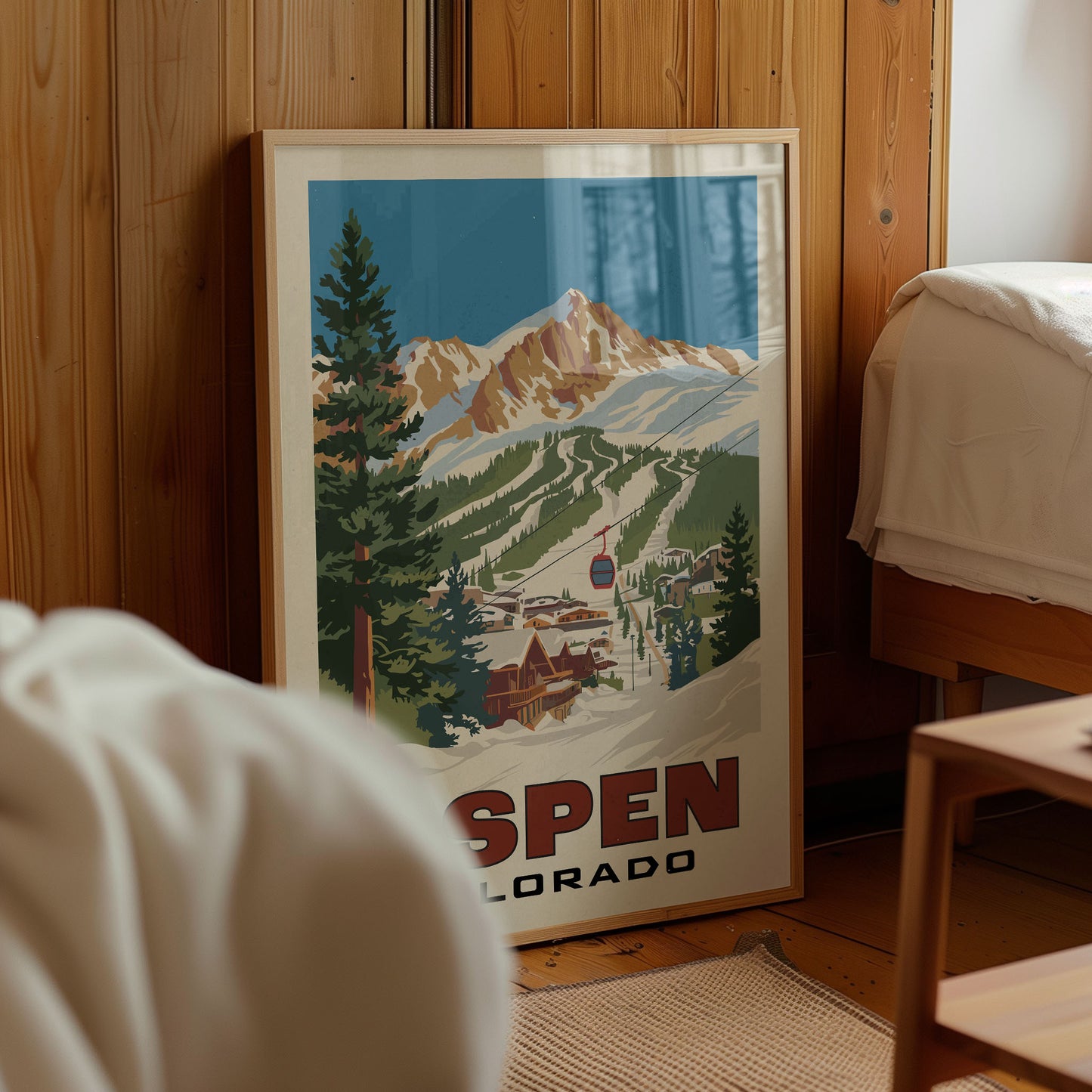 A framed poster of a mountain landscape with ski lifts and buildings, depicting the town of Aspen, Colorado.