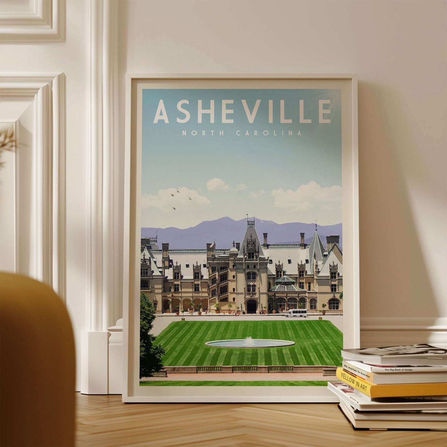 A framed poster of the Biltmore Estate in Asheville, North Carolina, displayed on a wall.