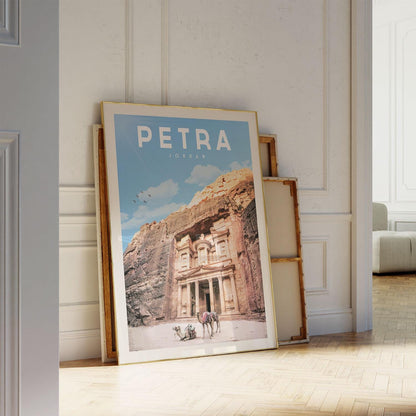 A framed poster of the ancient city of Petra, featuring the iconic rock-cut architecture of the Treasury of the Kings, is leaning against a white wall.