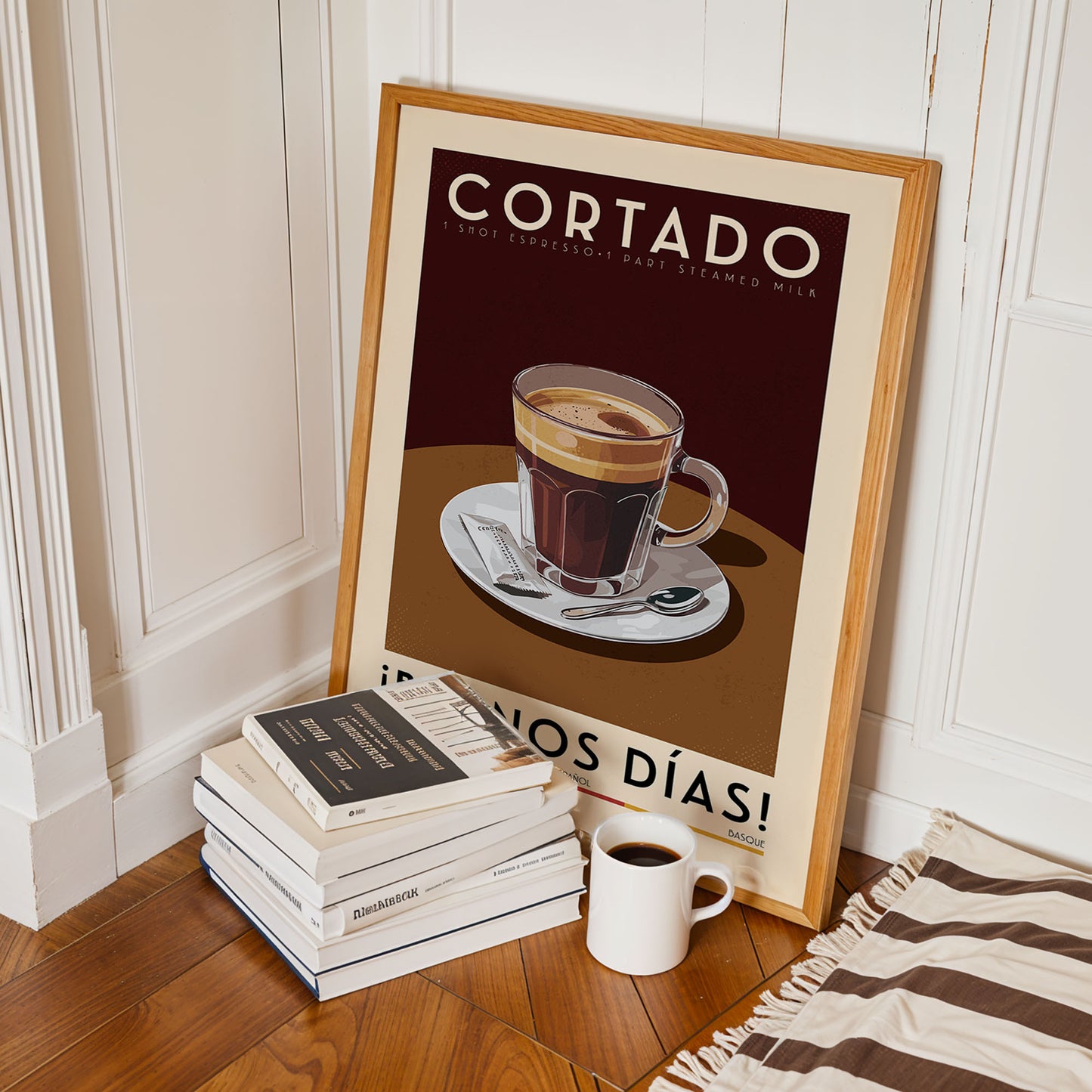 a framed poster of a cup of coffee with the text "CORTADO" and "I'M NOT EXPLOITING" on it, along with a stack of books and a white mug on a wooden floor.